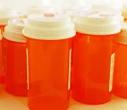 Orange plastic prescription pill containers with white lids 