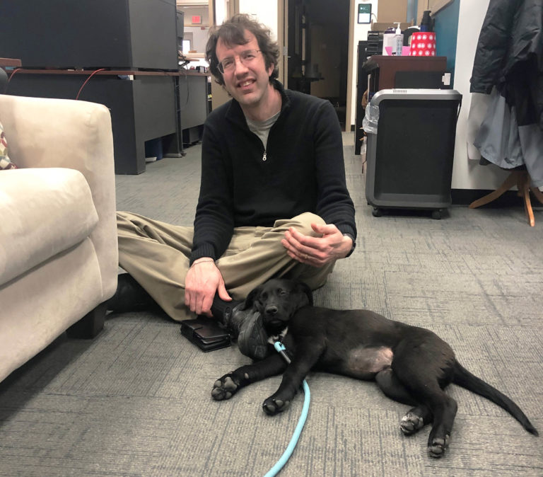 Alex Henkel with dog in office