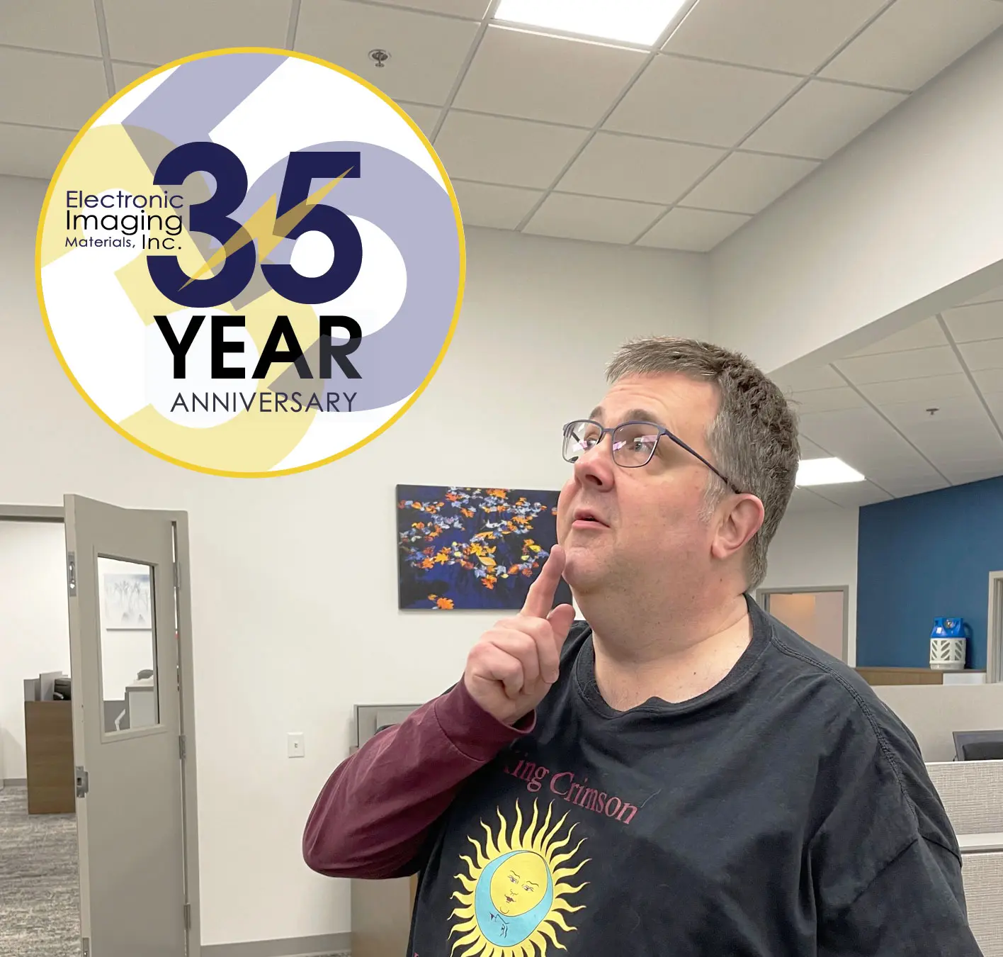 Retired Label Expert, Ed August poses thoughtfully with the EIM 35th Anniversary logo