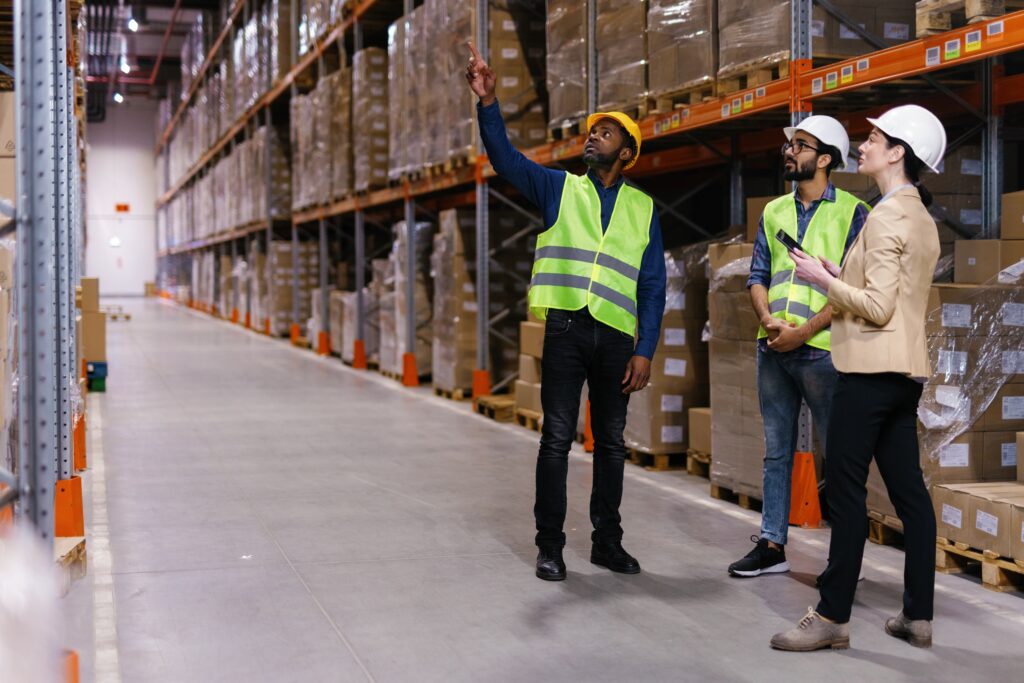 Three workers in a warehouse scanning an item on a shelf