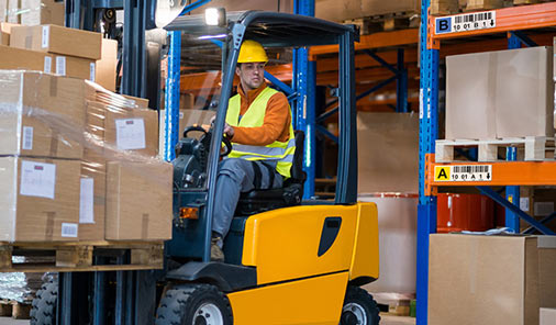 Barcode labeled warehouse storage racks with a forklift moving boxes