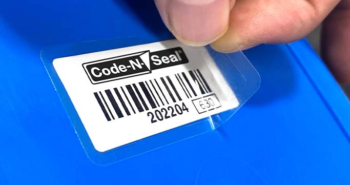 Close-up image of a hand applying a clear laminate over the top of an asset label header.