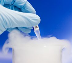 Person wearing a rubber glove holding a vial with a cryogenic label over a foggy lab cylinder - Pharmaceutical Testing labels