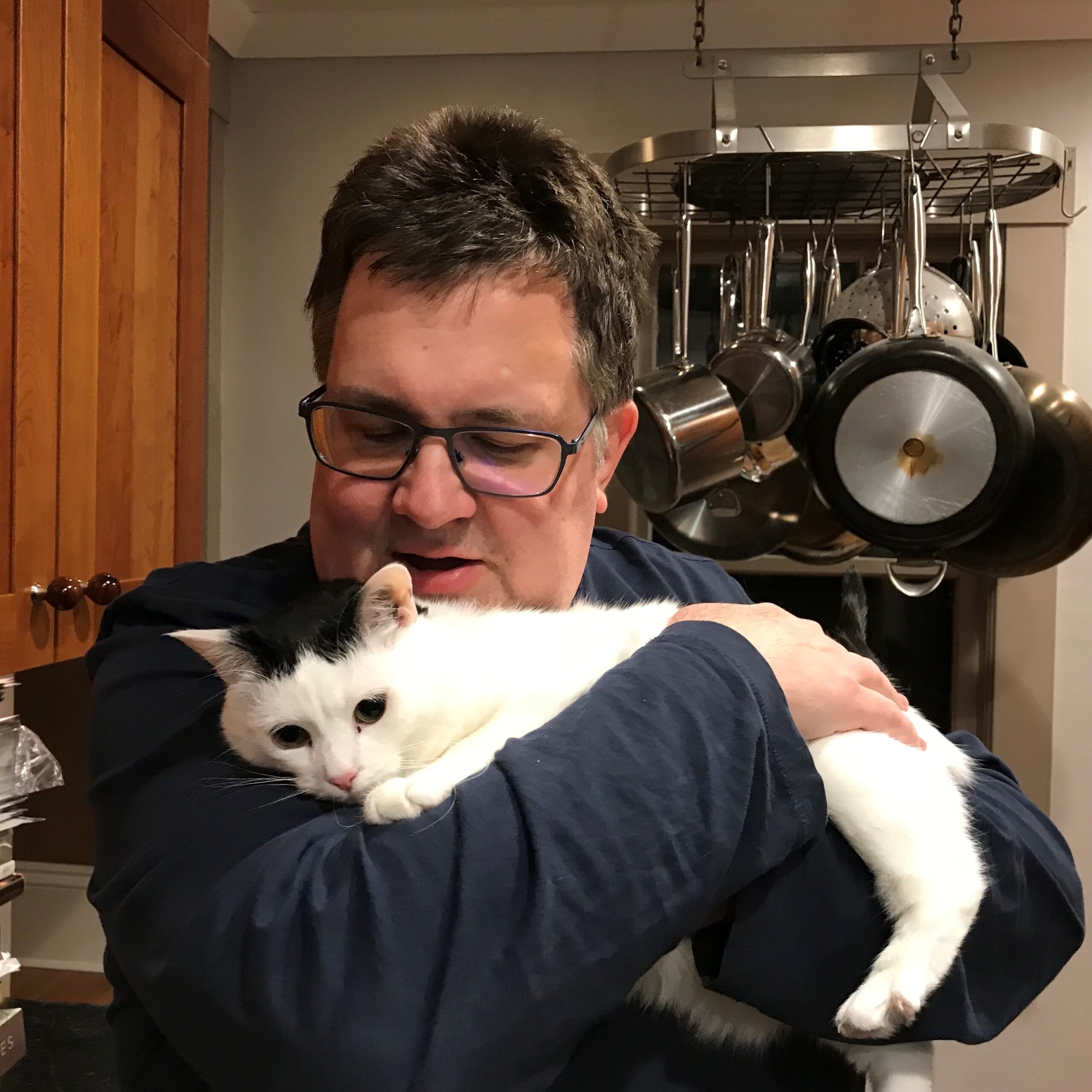 man in glasses holding a black and white cat