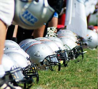 Youth Football Helmets laying in a row on grass outdoors