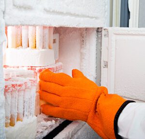 frozen vials in a cryogenic freezer, with outreached orange glove attempting to handle frozen vials 