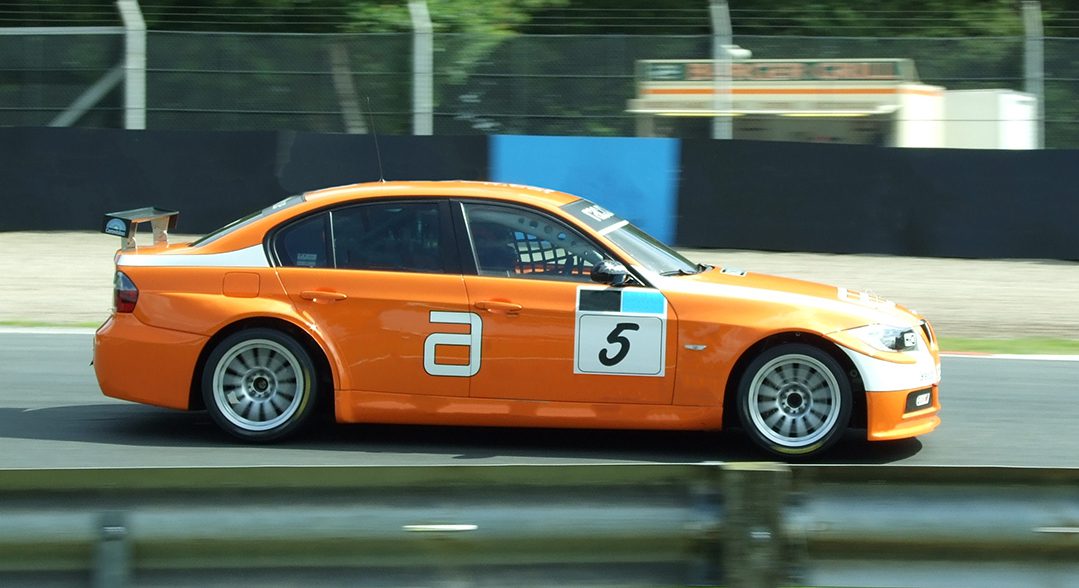 Orange Racecar speeding down the track 