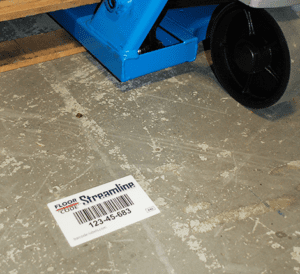 White barcoded warehouse floor label affixed to cement floor 