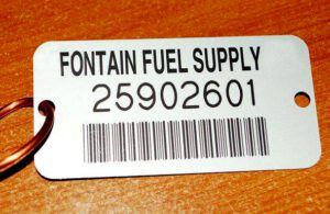 Grey metal tag with barcode and reading "Fontain Fuel Supply" 