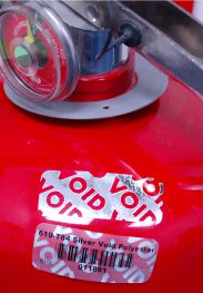 Leftover Void adhesive from peeled security label on a red fire extinguisher - void labels