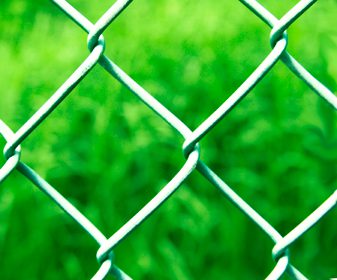 Chain linked fence with green grass in the background 