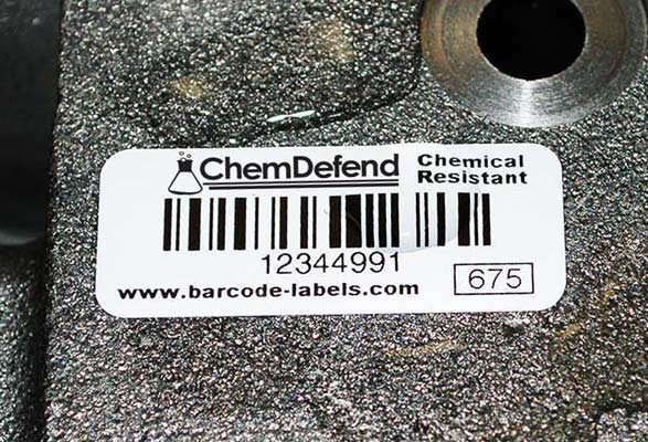 ChemDefend chemical resistant label on an industrial manufacturing part with chemical spilled