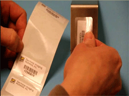 User placing a clear/laminate label on top of a smaller printed label