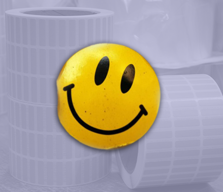 Smiley face sticker with label rolls in background