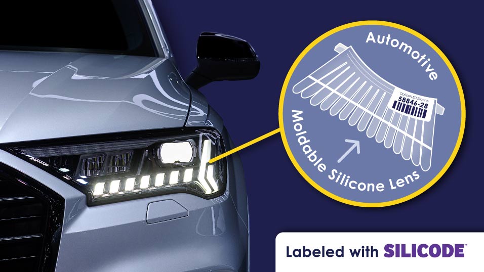 Automotive silicone lens labeled with a SiliCode barcode inside circle pointing towards car headlight