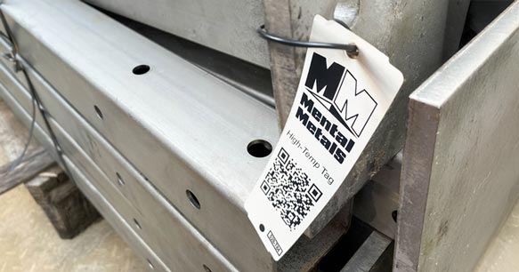 High temperature resistant plastic tag with logo and barcode attached to stacked steel beams.