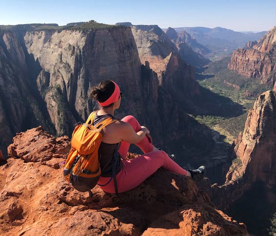 Label Expert Erin sitting on the edge of a canyon.