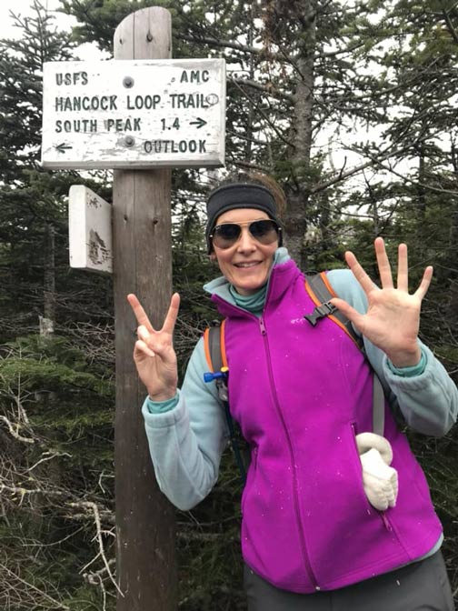 Erin standing outside in front of the Hancock Loop Trail sign.