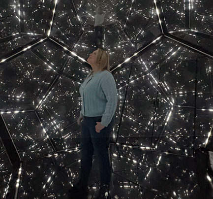 EIM's head of Human Resources Ashley in front of a reflective mirror art installation.