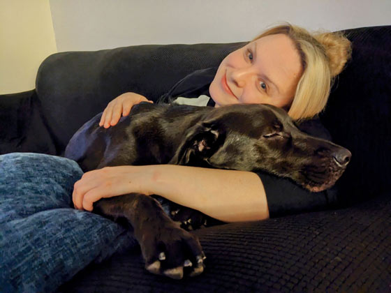 EIM Human Resources Ashley relaxing with her pet dog Bob Barker on a couch.