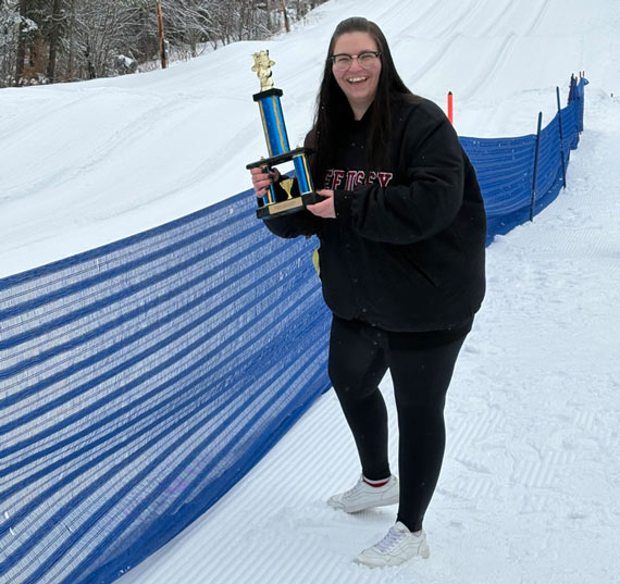 Tanya holding a trophy on a ski slope.