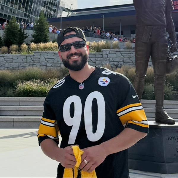 EIM Production Supervisor Jesus Mendoza posing outdoors in front of a sports stadium.